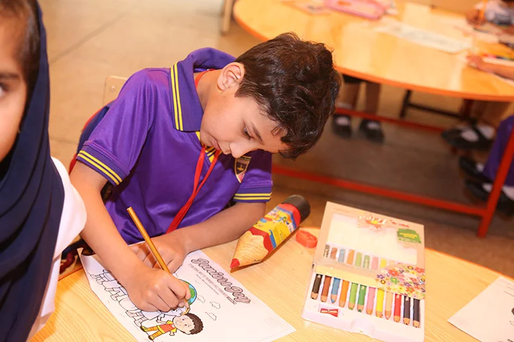 Boy coloring picture with crayons in classroom