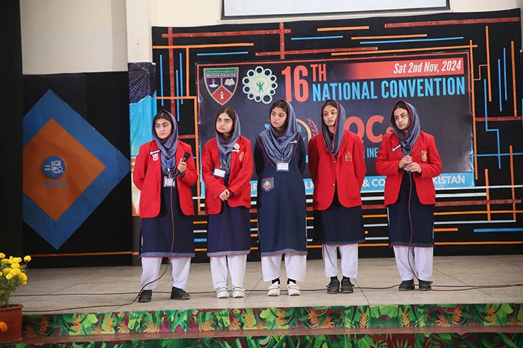 Female students presenting in red blazers on stage